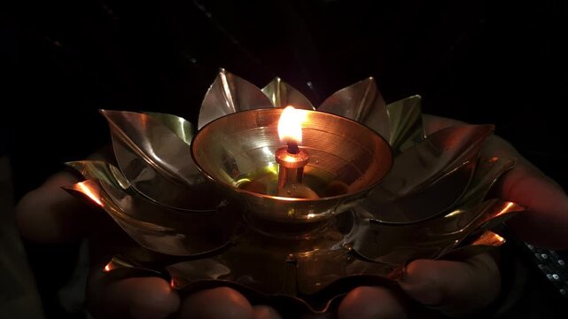 Beautiful Asian Indian girl holds a burning diya in her hands during the Diwali festival, celebrating Deepavali &mdash; the Hindu festival of lights &mdash; with a glowing traditional lamp in festive background.