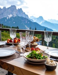 Elegant outdoor dining table set with gourmet food and wine glasses overlooking majestic mountain scenery.