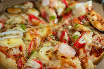 Abstract fine art macro image of seafood pizza surface showing rich colors and textures of baked cheese and toppings.