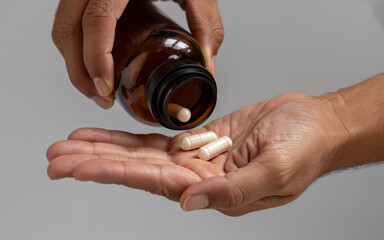 Boosting wellness with vital supplements, pouring out capsules for daily dose, embracing proactive healthcare and empowering personal well-being initiatives