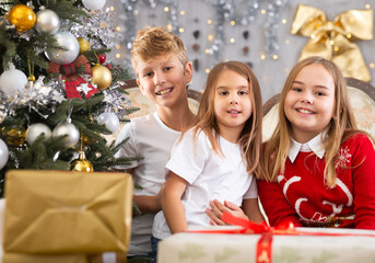 Two girls and boy on sofa in Christmas interior