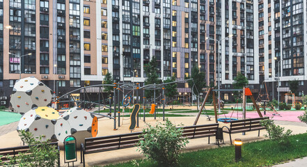 Modern residential courtyard with children s playground including climbing structures, swings and benches surrounded by high-rise apartment buildings, symbolizing urban lifestyle and community leisure © Evgeniia Primavera