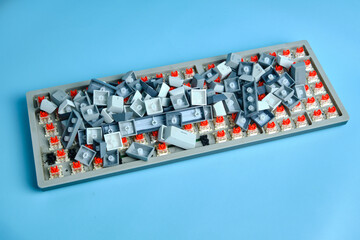 A mechanical keyboard base with all keycaps piled in the center, showing the exposed red switches.