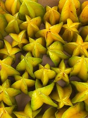 Fresh starfruit (carambola) displayed at a local market. Exotic tropical fruits in vibrant yellow tones. Organic and healthy food background.