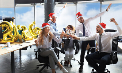 Business people are celebrating holiday in modern office drinking champagne and having fun in coworking. Merry Christmas and Happy New Year 2026