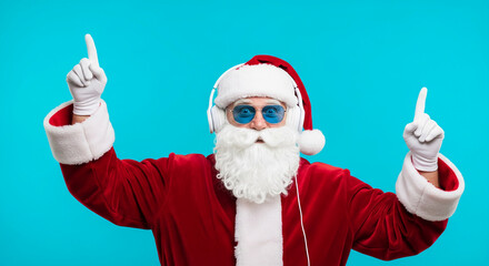 Image of person in Santa Claus costume with headphone and sunglass, pointing upward against turquoise background, symbolizing Christmas and celebration