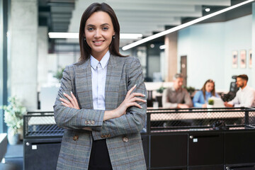 Handsome successful businesswoman looking camera hands crossed friendly chief standing at modern office indoors