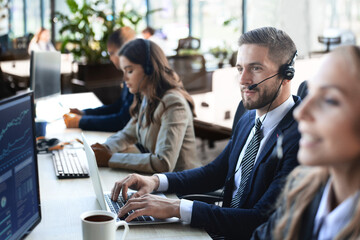 Portrait of call center worker accompanied by his team. Smiling customer support operator at work.