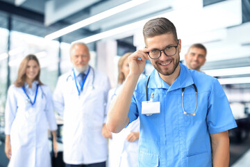 Smiling doctor holding tablet in front of his medical team.
