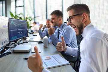 Group of modern business men in formalwear smiling and gesturing while working in the office.