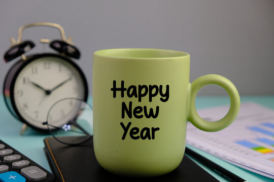 text of HAPPY NEW YEAR on the green cup of coffee and pen. business concept