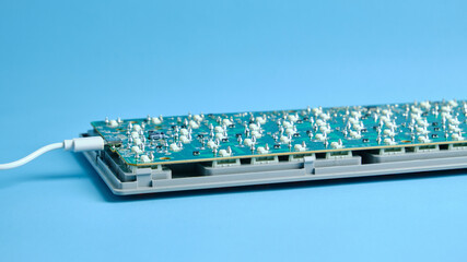 Electronic Keyboard Circuit Board on a Desktop Keyboard Base Against Blue Background