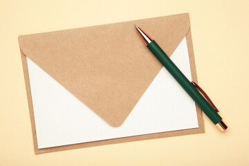 Craft envelope with paper card and green pen on beige background