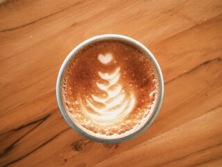 A cup of cappuccino coffee served on wooden table