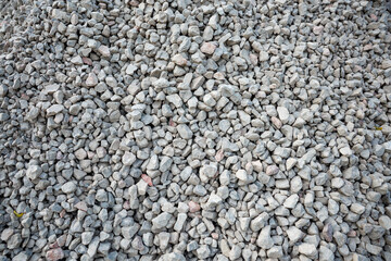 Obraz premium A detailed view of a pile of small gray stones with irregular shapes, featuring scattered hints of pink and beige tones across the rugged surface.