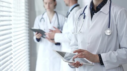 Medical professional using a digital tablet for patient care and data management, collaborating with doctors and healthcare workers in a modern clinic or hospital setting - Powered by Adobe