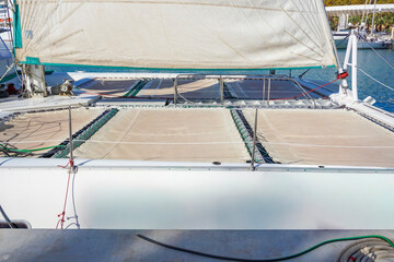 close up of the netting trampolines and foresail of a catamaran docked in a marina, concept of sailing, yachting, summer vacation, marine leisure