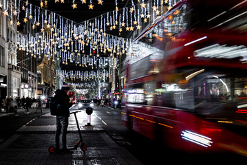 Classic red double-decker bus on festive London street at night