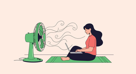 Fototapeta premium A woman sits on a mat working on her laptop while a fan blows air on her to cool her down.