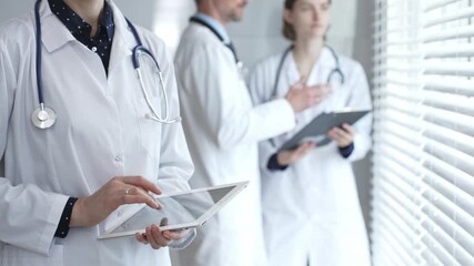 Medical professional using a digital tablet for patient care and data management, collaborating with doctors and healthcare workers in a modern clinic or hospital setting - Powered by Adobe