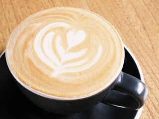 a cup of magic cappuccino coffee served on wooden table
