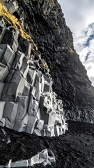 Dramatic view of layered rock formations on a dark sand beach
