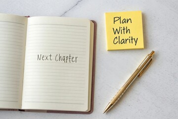 An open journal and sticky note next to a pen on a marble surface, ready to plan