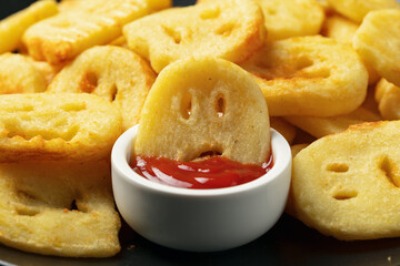 Fried Halloween potato shapes on black plate.