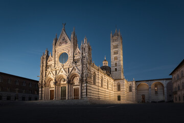 Obraz premium Night cityscape with illuminated facade of Duomo di Siena gothic cathedral and empty square, Italy