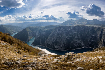 Sunlit mountains landscape, Piva Canyon, forested steep slopes, azure water bending river,...