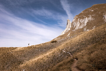 Mountain landscape with female tourist walking to rocky cliff on sunny day, Durmitor, Montenegro