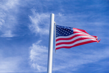 American Flag Waving In The Wind Against A Blue Sky With Clouds And Symbolizing Patriotism And National Pride.