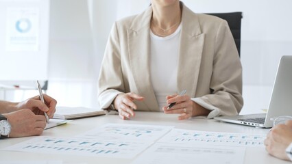 Professional team reviewing financial charts, collaborating on data analysis and strategic planning in modern corporate workspace, emphasizing teamwork and productivity