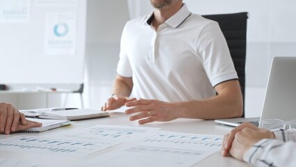 Professional team reviewing financial charts, collaborating intently around conference table in contemporary workspace, sharing insights during strategic planning session