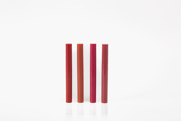A row of five red lipsticks are displayed on a white background. The lipsticks are all different shades of red, ranging from light pink to deep burgundy. Concept of variety and choice.