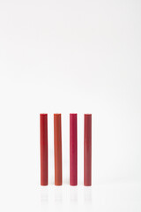 Four red lipsticks are lined up next to each other. The lipsticks are all different shades of red, and they are all lined up in a row. Concept of organization and order.
