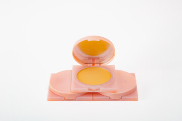 Three small containers of yellow powder are stacked on top of each other. The containers are pink and have a reflective surface. Concept of organization and order.