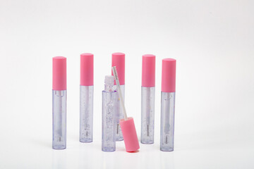 A row of six pink lipsticks with a clear tube. The lipsticks are all the same color and are sitting on a white background.