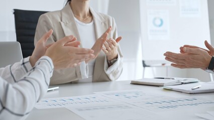 Professional business team clapping hands, celebrating successful presentation, displaying collaborative spirit and workplace enthusiasm in modern office setting