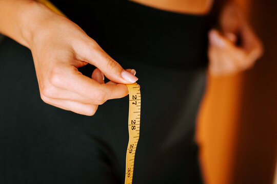 Measuring waist size with tape during fitness journey at home