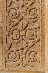 A close-up reveals a detailed, weathered stone carving of a symmetrical floral motif