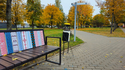 Colorful bench in autumn park surrounded by golden trees  