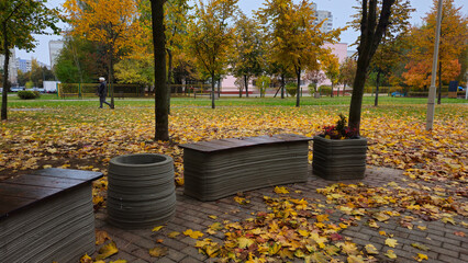 Outdoor benches made from concrete using a 3D printer surrounded by colorful autumn leaves in park  
