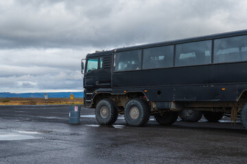 Obraz premium Large Black Off Road Bus on Wet Asphalt in Remote Icelandic Landscape