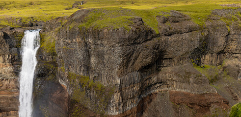 Icelandic Waterfall Cascading Over Basalt Columns and Lush Terrain