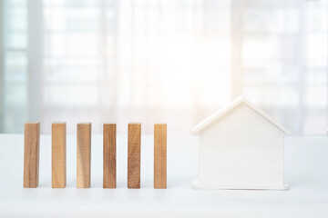 Wooden blocks arranged in rows and white house with blurred window background. Real estate business concept.