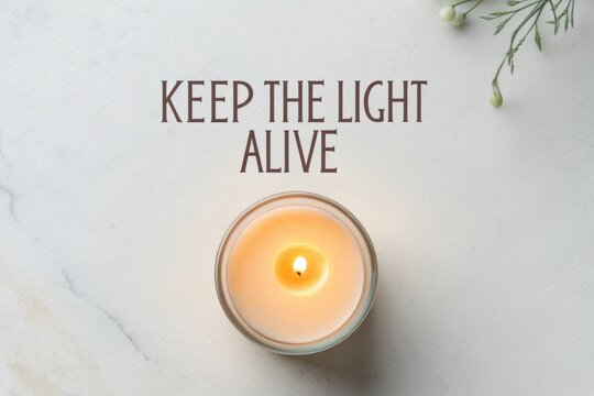 Burning candle with glowing light on a pale stone background