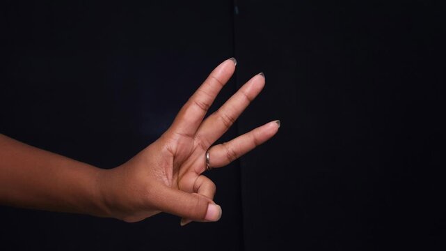 Close-up female hands expressing hand gesture with fingers isolated on black background.
