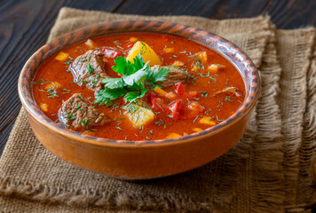 Rustic clay bowl filled with traditional Hungarian Bogracs stew on wooden table