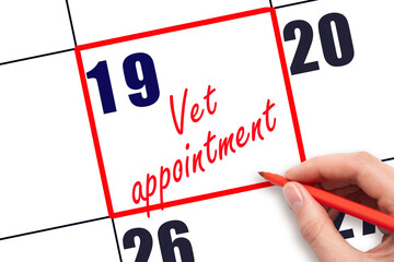 19 th day of the month. Hand writing Vet appointment reminder and drawing red frame on calendar...